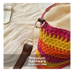 Detail of gold metal hook and brown leather strap on colorful woven straw beach bag