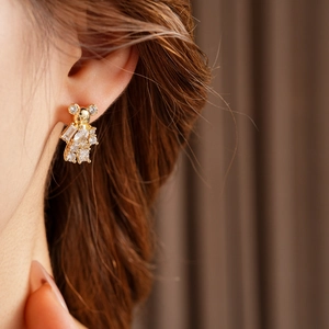 Detailed view of a gold-plated bear stud earring with sparkling zircon on a model's ear