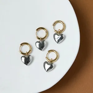 Minimalist heart charm hoop earrings in gold and silver finish on white tray