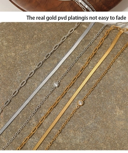 Macro detail of multi-layered PVD gold plated chain necklaces on a stone surface