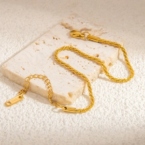 Detail of 18k gold plated stainless steel chain with lobster clasp on white stone
