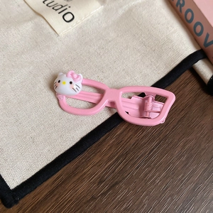 Detailed close-up of a pink glasses-shaped hair clip featuring a cute cartoon cat character
