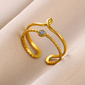 Detailed close-up of a double-layer gold ring with twisted texture and blue gemstone