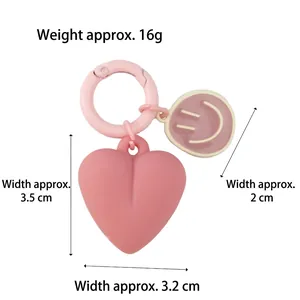 Pink heart keychain with cartoon smiley face charm and round snap hook for bags