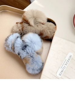 Detail view of two large plush rabbit fur hair claws in brown and blue on a gold tray