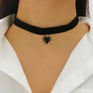 Detail of a black velvet choker featuring a shimmering glittery black heart pendant