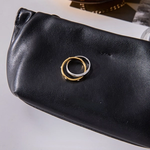 Macro shot of interlocking gold and silver geometric rings on a black leather texture pouch