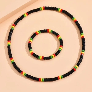Detail of colorful black green yellow and red beaded necklace and bracelet set on peach background