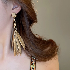 Detailed view of long gold tassel earrings with leaf-shaped pendants and hammered texture