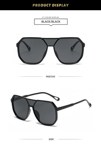 Detail view of black oversized geometric sunglasses with thick top bar and grey lenses