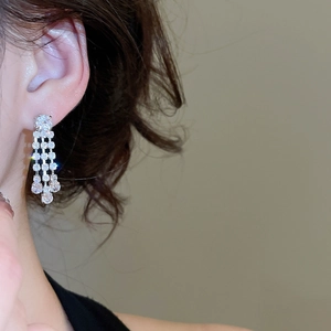 Close-up of a model wearing sparkling zircon square fringe earrings in silver finish