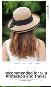 Detail of a beige straw sun hat featuring a black wide ribbon and elegant side bow