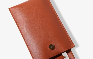 Detailed close-up of brown synthetic leather mobile bag with golden magnetic clasp