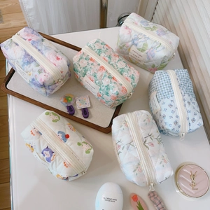 Flat lay of multiple floral and plaid quilted cotton makeup bags in various patterns