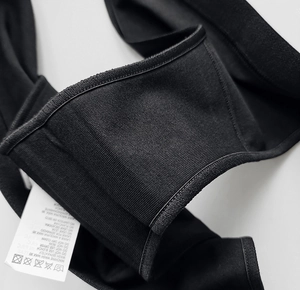 Macro shot of breathable black cotton fabric texture and laundry care label detail