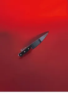 Detailed view of creative kitchen knife hair clip with metal spring clasp on red background