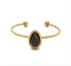 Detail of a gold adjustable ring featuring a black water-drop stone with white marble texture