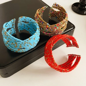 Détail de manchettes multicouches en perles de verre bleues, dorées et rouges à motifs