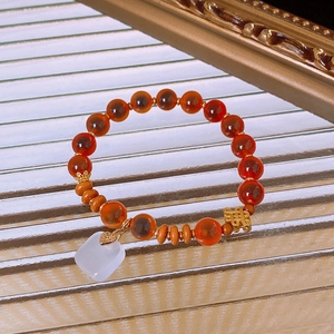 Detailed shot of red agate beaded bracelet with white jade square charm and gold knot