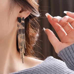Close-up of black and gold tassel earrings with rhinestones on a female model