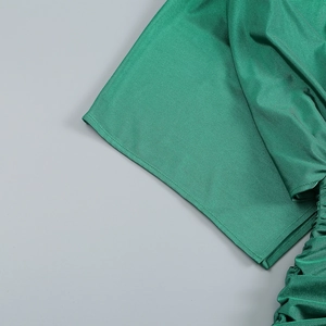 Dettaglio macro dell'abito in raso verde smeraldo con eleganti increspature laterali