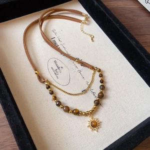 Detail of vintage bohemian layered necklace with tiger eye beads and sun pendant