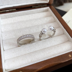 Close-up of zircon ring set with double pearls on a velvet walnut jewelry box