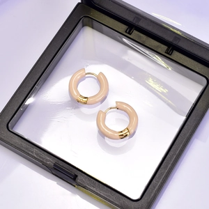 Détail de boucles d'oreilles créoles à l'émail rose et placage or 18 carats sur acier
