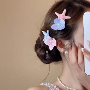 Detail of starfish and flower hair clips with pearls on model's braided hair