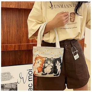 Close-up of small canvas tote bag featuring exquisite triple cat jacquard embroidery