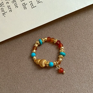 Detailed shot of ethnic stretch ring with turquoise beads and gold gourd pendant