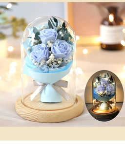 Close-up of blue rose in glass dome with warm LED lighting and wooden base