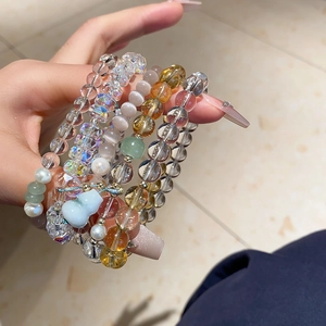 Detail of layered beaded bracelets with chalcedony, crystal, and blue gourd charm