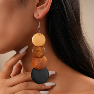 Detail of four-tier bohemian wooden disc earrings worn on ear with tiered multicolor beads