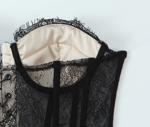 Detailed close-up of black eyelash lace trim and side lace-up tie design on a corset top