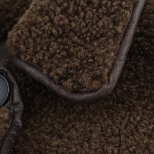 Close-up of brown faux shearling jacket with leather piping and black button details