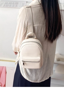 Close-up of the pebbled leather texture and silver zipper on the beige crossbody bag
