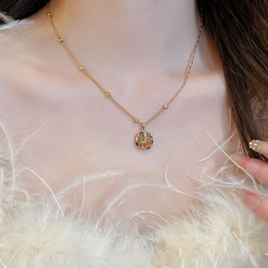 Detail of gold plated necklace with colorful zircon stones worn against white feathers