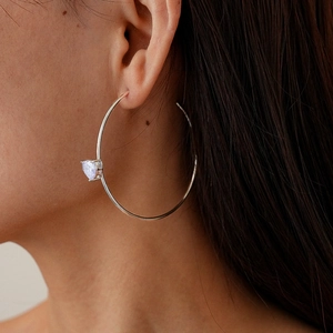 Detail of silver C-shaped hoop earring with heart-shaped zircon on a side-profile model