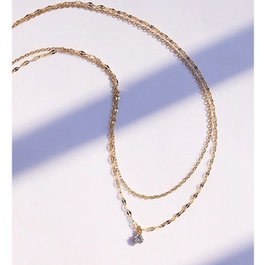 Detail of double-layer gold chain necklace with petal links and a zircon pendant
