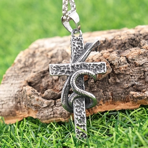 Macro view of vintage silver snake wrapped cross pendant on aged wood texture