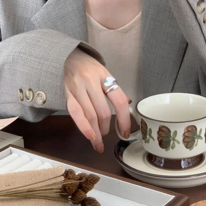 Close-up of a minimalist irregular 925 silver ring worn while holding a coffee cup