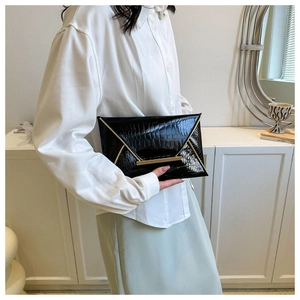 Macro detail of black crocodile leather envelope clutch with elegant gold metal trim