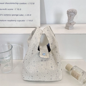 Detail van canvas tas met zilveren sterren en blauwe hartknop op witte treden