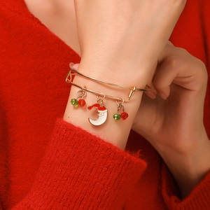Adjustable gold Christmas bracelet with Santa moon charm and beads on a red sweater background