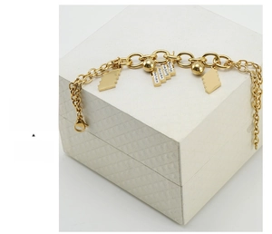 Dettagli dei pendenti geometrici dorati e cristalli su un bracciale in acciaio inossidabile