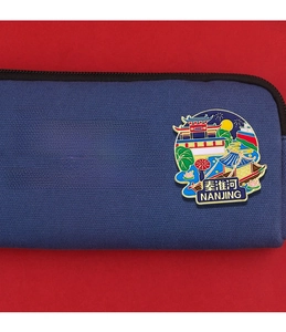 Detail of dark blue canvas bag with enamel pin featuring Qinhuai River scenery