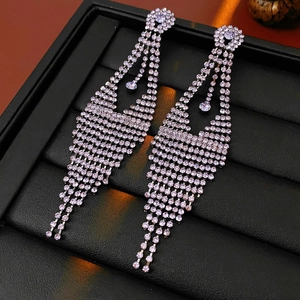 Détail de boucles d'oreilles argentées à franges et cristaux brillants sur support noir