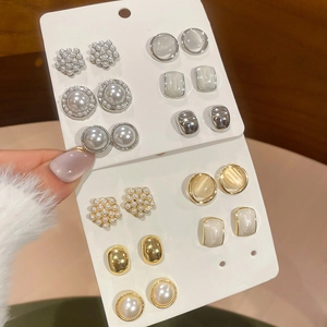 Detail view of gold and silver stud earring set with pearls and rhinestones on hand