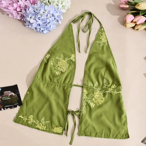 Detail of green halter top with yellow floral embroidery and sequins on fabric